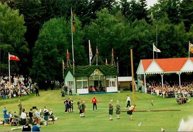 A kilted competitor throws at the Braemar Gathering, watched by crowds outside the flag-draped Royal Pavilion.