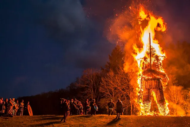 A large wickerman burns at night in front of a watching crowd at the Beltain festival, Butser Ancient Farm.