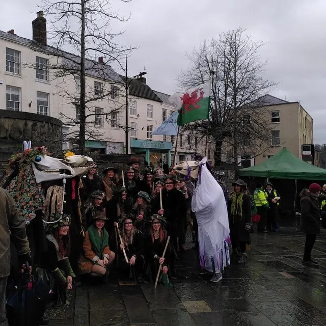 Morris dancers and the Mari Lwyd horse-skull gather in Chepstow for the wassail, with the Welsh flag flying behind.