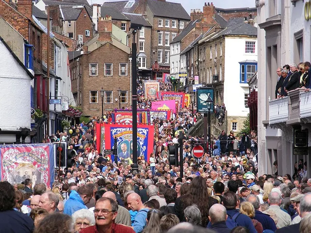 Union banners and bands fill a dense crowd on a Durham street below the old town skyline during the Miners' Gala.