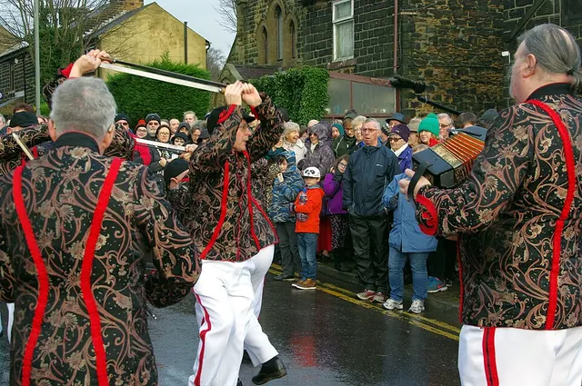 A Grenoside sword dancer raises his blade as the team perform in the street on Boxing Day, watched by a crowd.