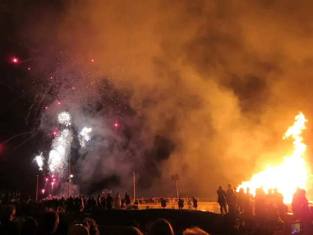 Fireworks burst over a blazing bonfire and crowd on Pelham Beach during Hastings Bonfire Night.