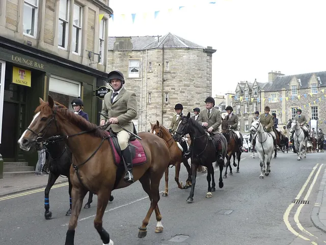 Mounted riders in hunting dress lead a line of horses down a bunting-hung street in Hawick during the Common Riding.