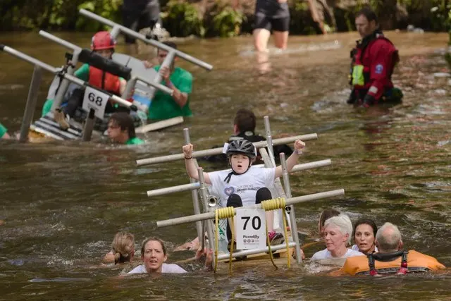 A team pushes a bed mounted on a wheeled float through the River Nidd during the Knaresborough Bed Race.
