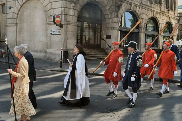 Red-coated watermen, a verger and civic dignitaries process through a City of London street during the Knollys Rose ceremony.