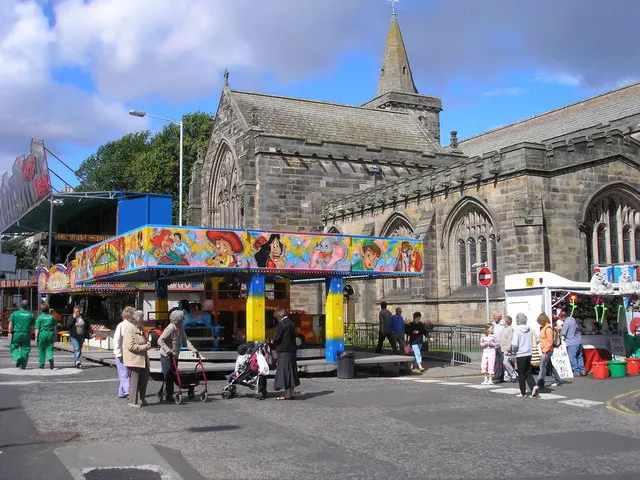 A fairground ride's colourful canopy stands in St Andrews' South Street in front of the parish church during Lammas Market.