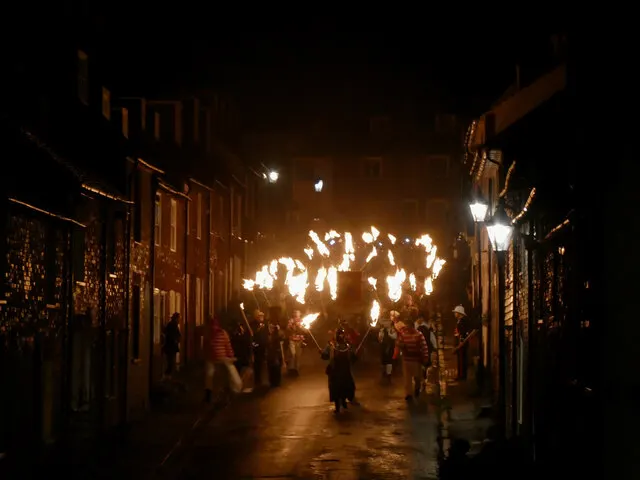 Torchbearers process down a narrow Lewes street lit only by flame on Bonfire Night.