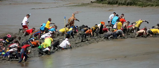 Competitors in fancy dress crawl and leap through the tidal mud of the River Blackwater during the Maldon Mud Race.