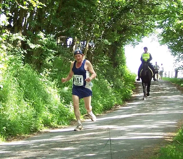 A runner and a horse-and-rider pass on a country lane during the Man versus Horse Marathon near Llanwrtyd Wells.
