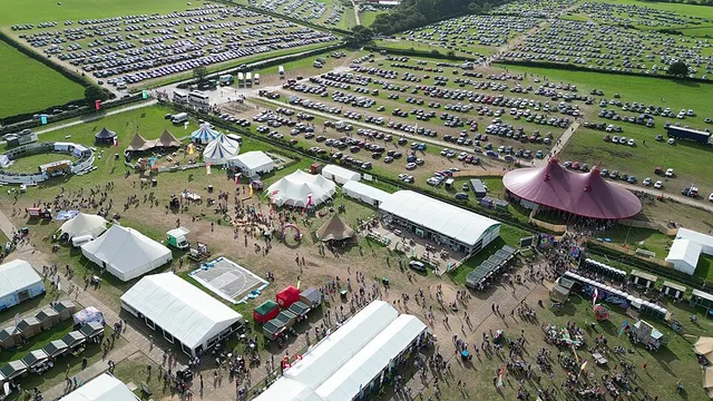 An aerial view shows the National Eisteddfod's tented Maes and car parks filling a green field.