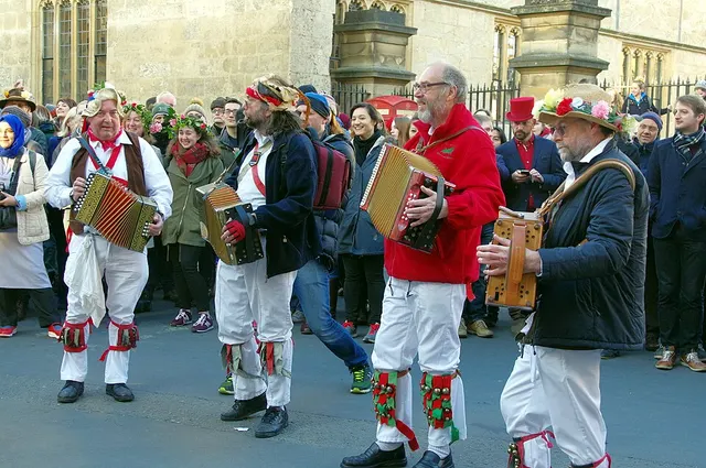 Morris dancers and an accordion player perform on the street among the crowd during May Morning in Oxford.