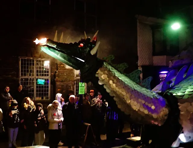 A dragon float breathes fire over the crowd during the Rye Bonfire procession in 2024