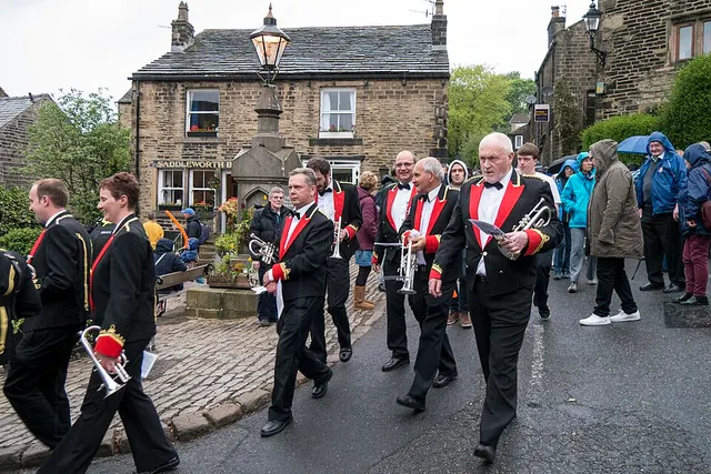 A brass band in braided uniforms marches through a Saddleworth village during the Whit Friday brass band contests.