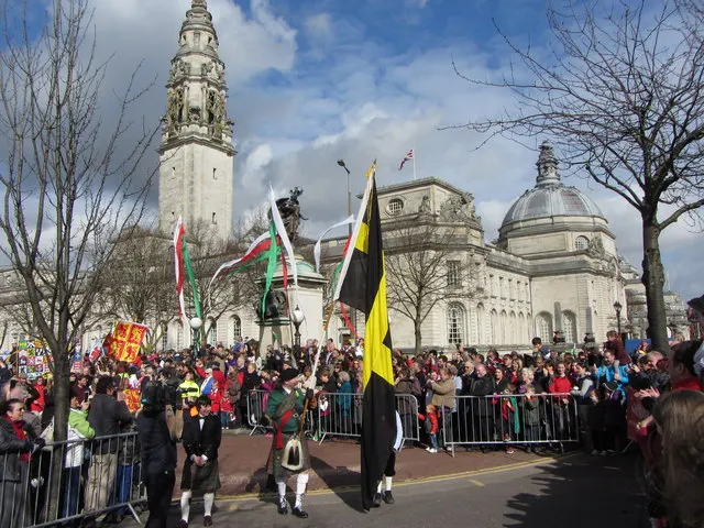 Flag-bearers in Welsh dress lead the National St David's Day Parade past Cardiff City Hall's clock tower.