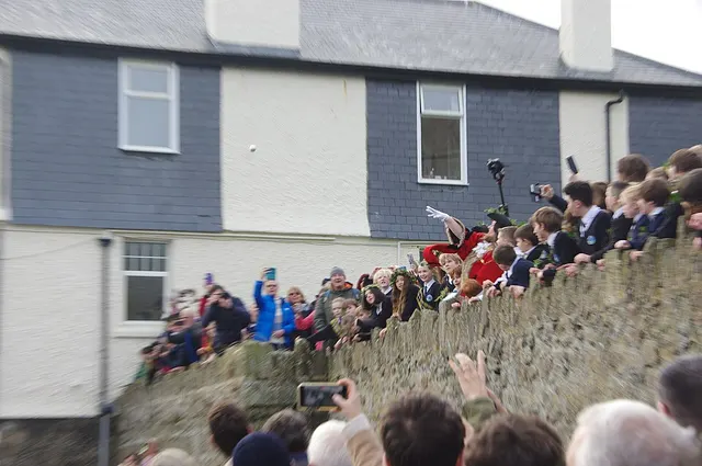 The Mayor of St Ives, in scarlet robes on the harbour wall, hurls the silver ball into the air above a waiting crowd of garlanded children.