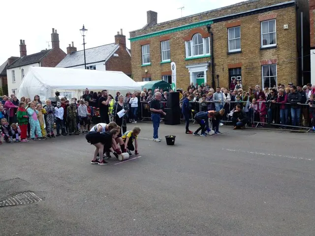 Two teams crouch to roll a wooden 'cheese' along the course in front of a watching crowd at the Stilton Cheese Rolling festival.