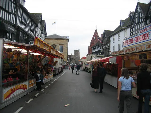 Food stalls line a Stratford-upon-Avon street of half-timbered buildings during the Mop Fair.