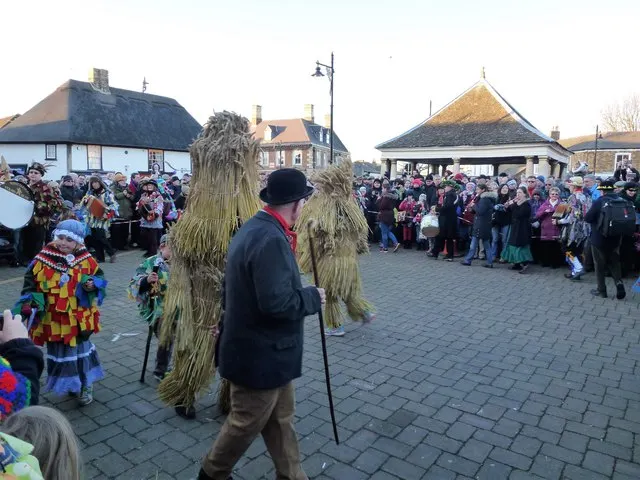 Straw-costumed figures gather in Whittlesey's Market Place as crowds watch the Straw Bear Festival procession.