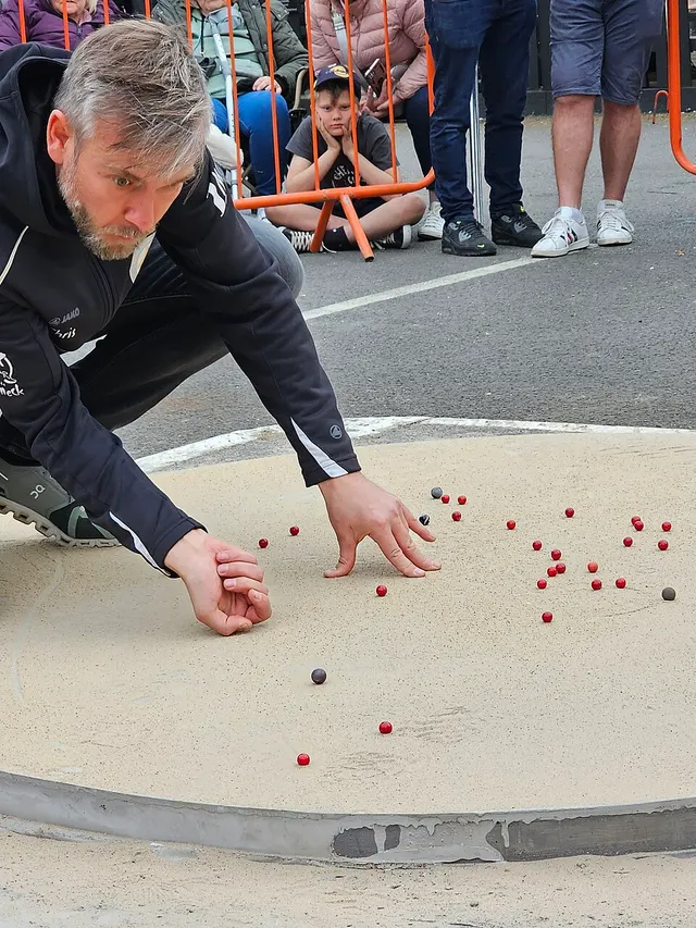A player crouches over the sand ring to shoot a marble at the British and World Marbles Championship in Tinsley Green.