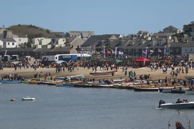 Rows of Cornish pilot gigs lie beached at Hugh Town, Isles of Scilly, with crews and crowds gathered for the World Pilot Gig Championships.
