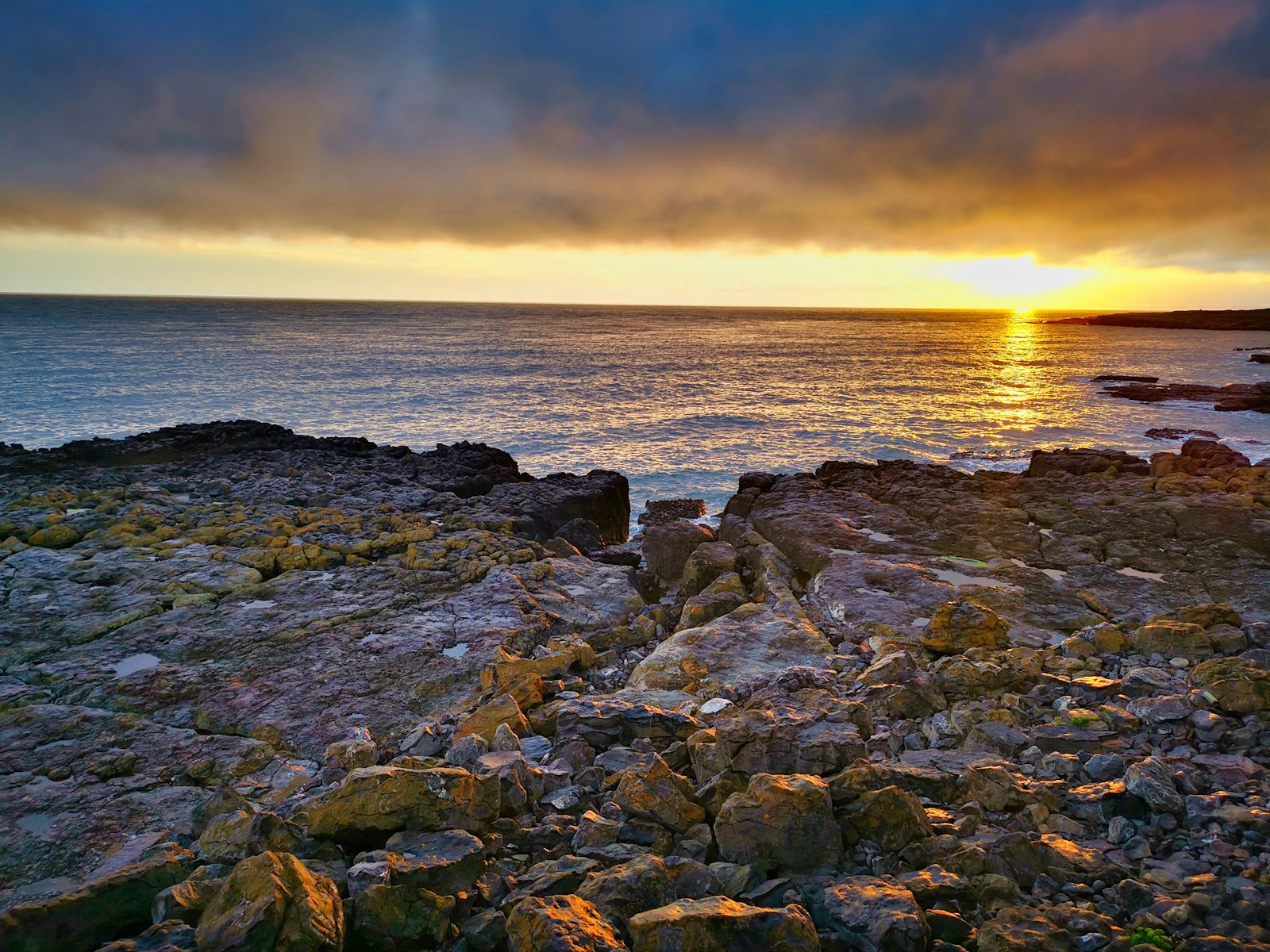 Photo of brown rocky shore during sunset.