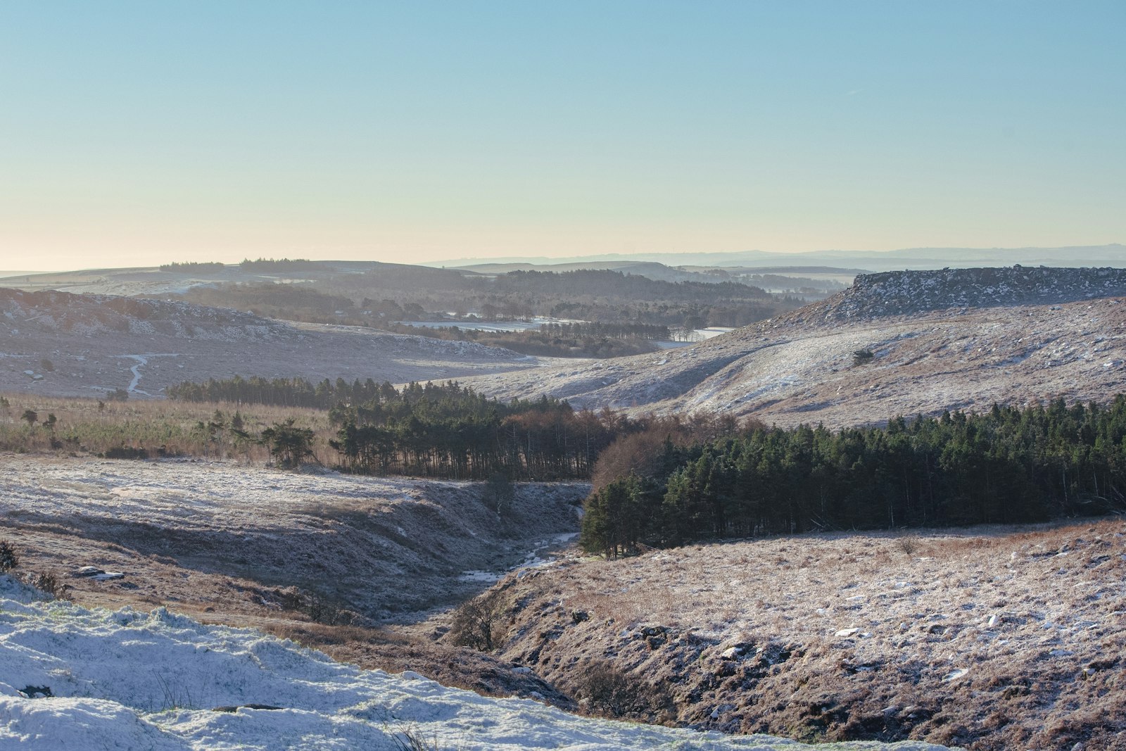 Photo of a view of a snowy landscape with trees in the distance.