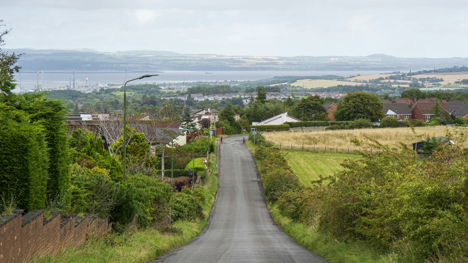 Photo of a road with trees and buildings on the side.