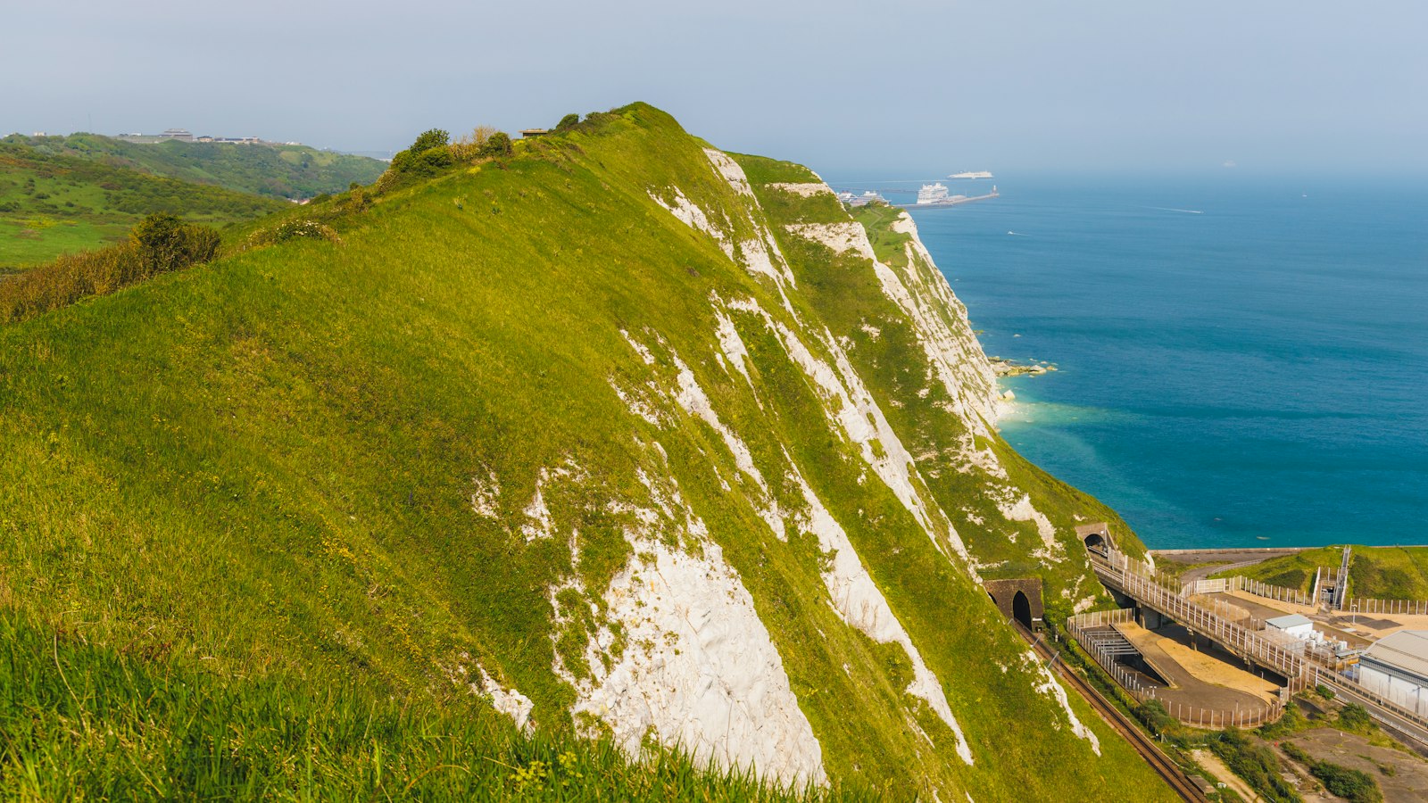 Photo of a grassy hill with a large body of water in the background.