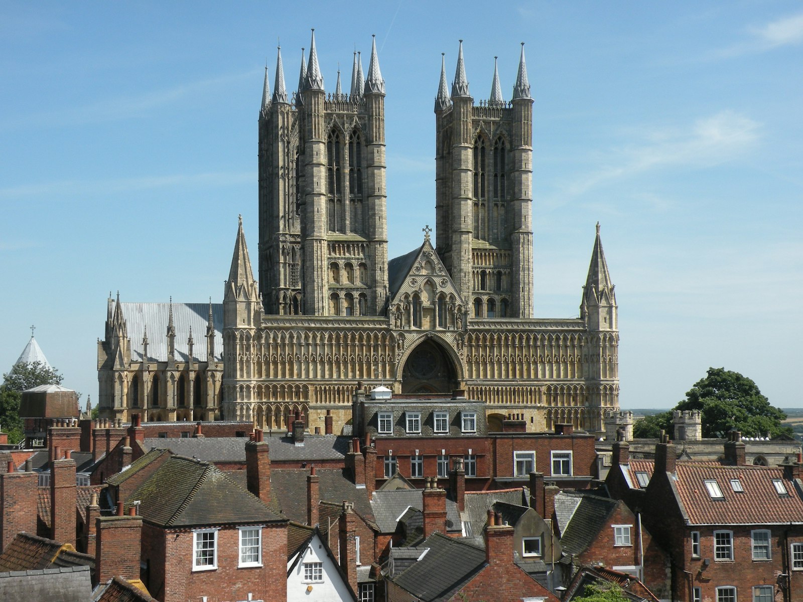 Photo of Lincoln cathedral viewed over rooftops under a clear sky.