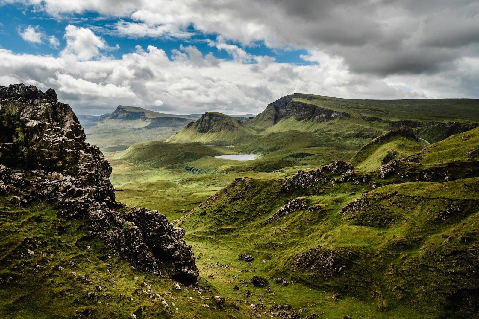 Photo of green grass on mountain under white cloudy sky.