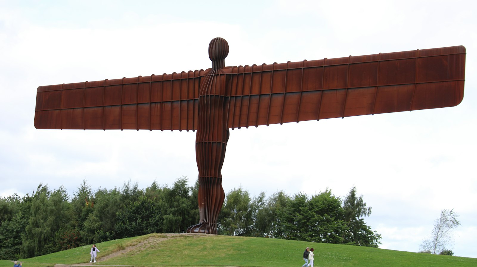 Photo of a large metal angel statue on top of a hill.