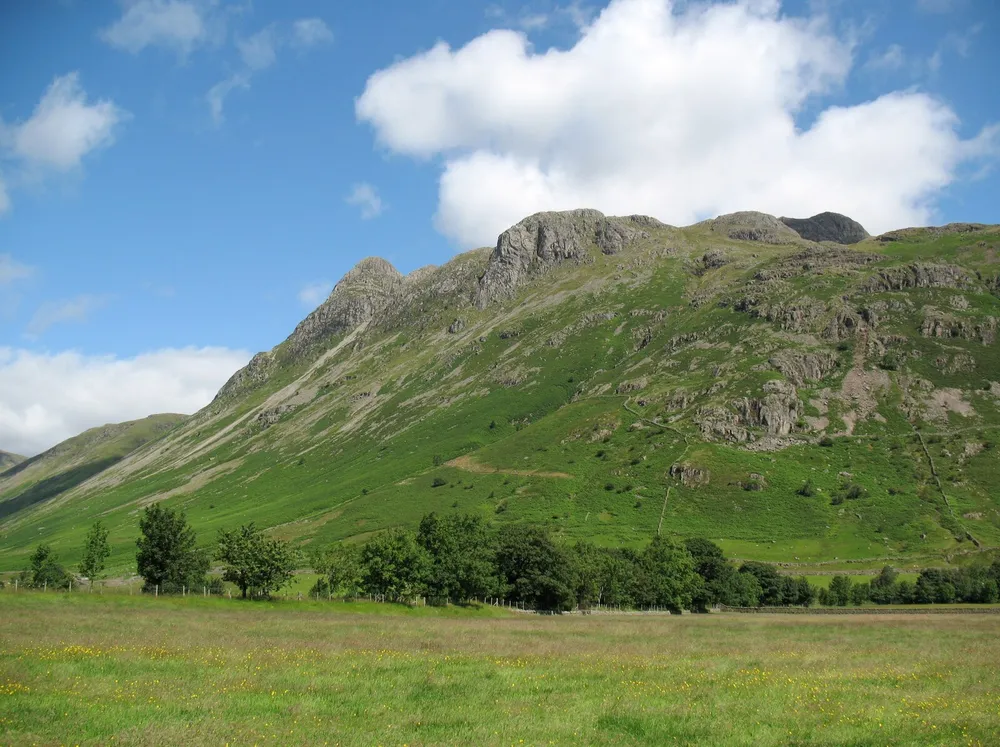 Photo of the Langdale Pikes rising above green fields in Great Langdale, Lake District