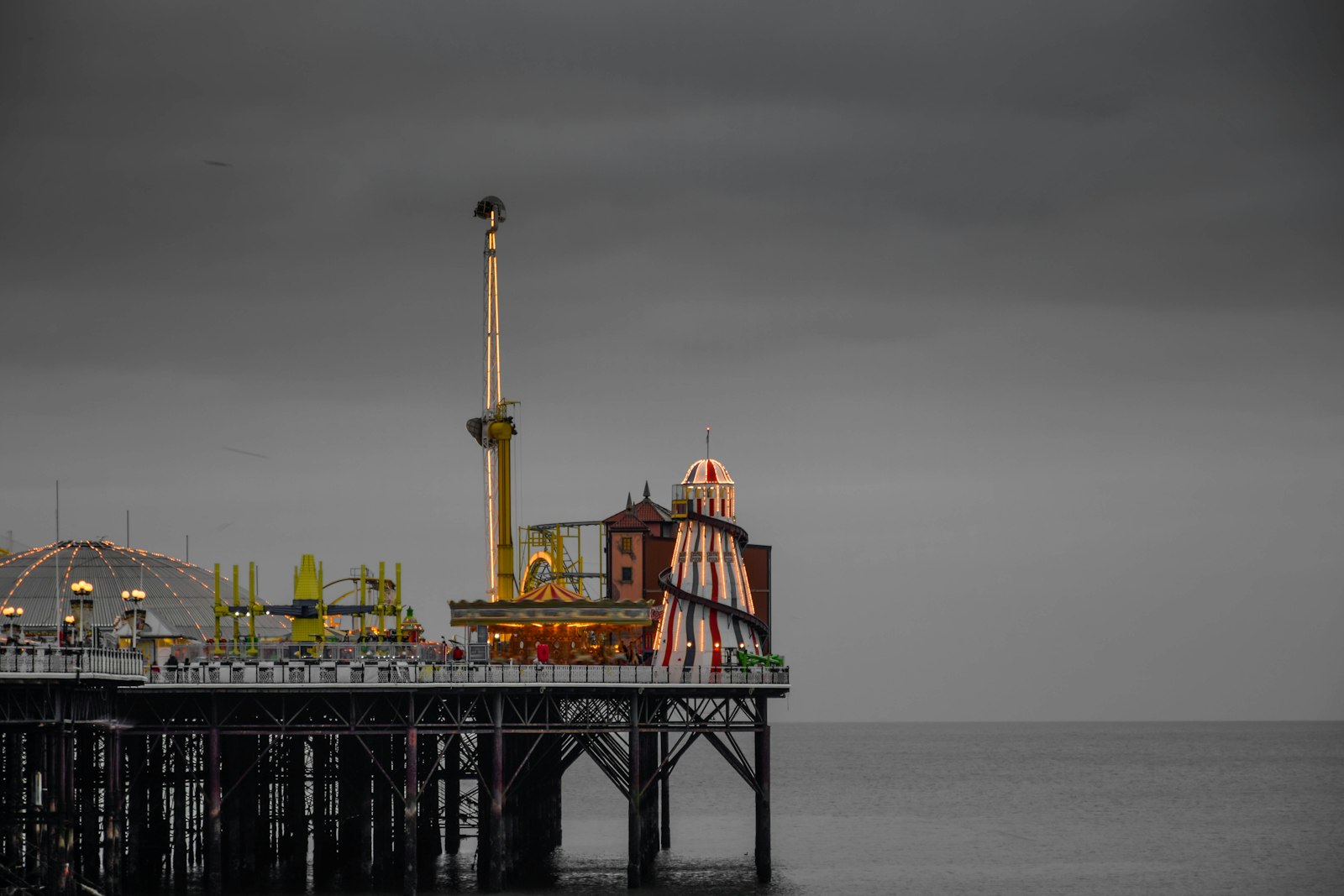 Photo of a pier with a ferris wheel and a ferris wheel in the distance.