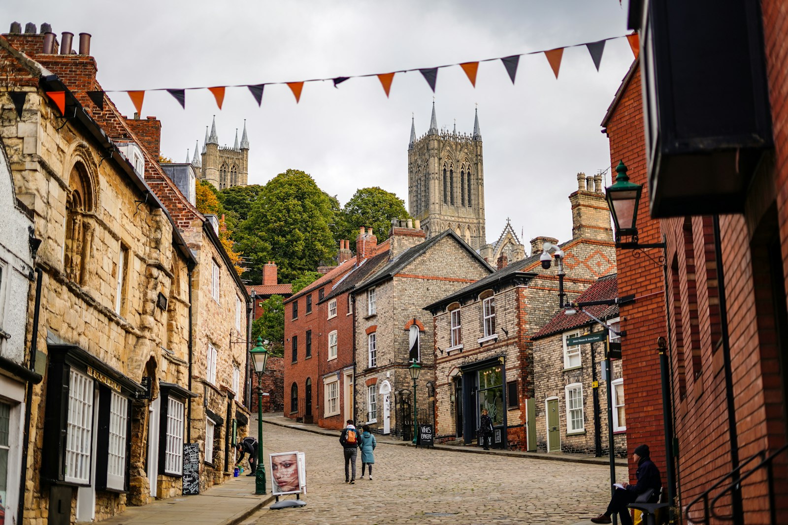 Photo of a cobblestone street with people walking on it.