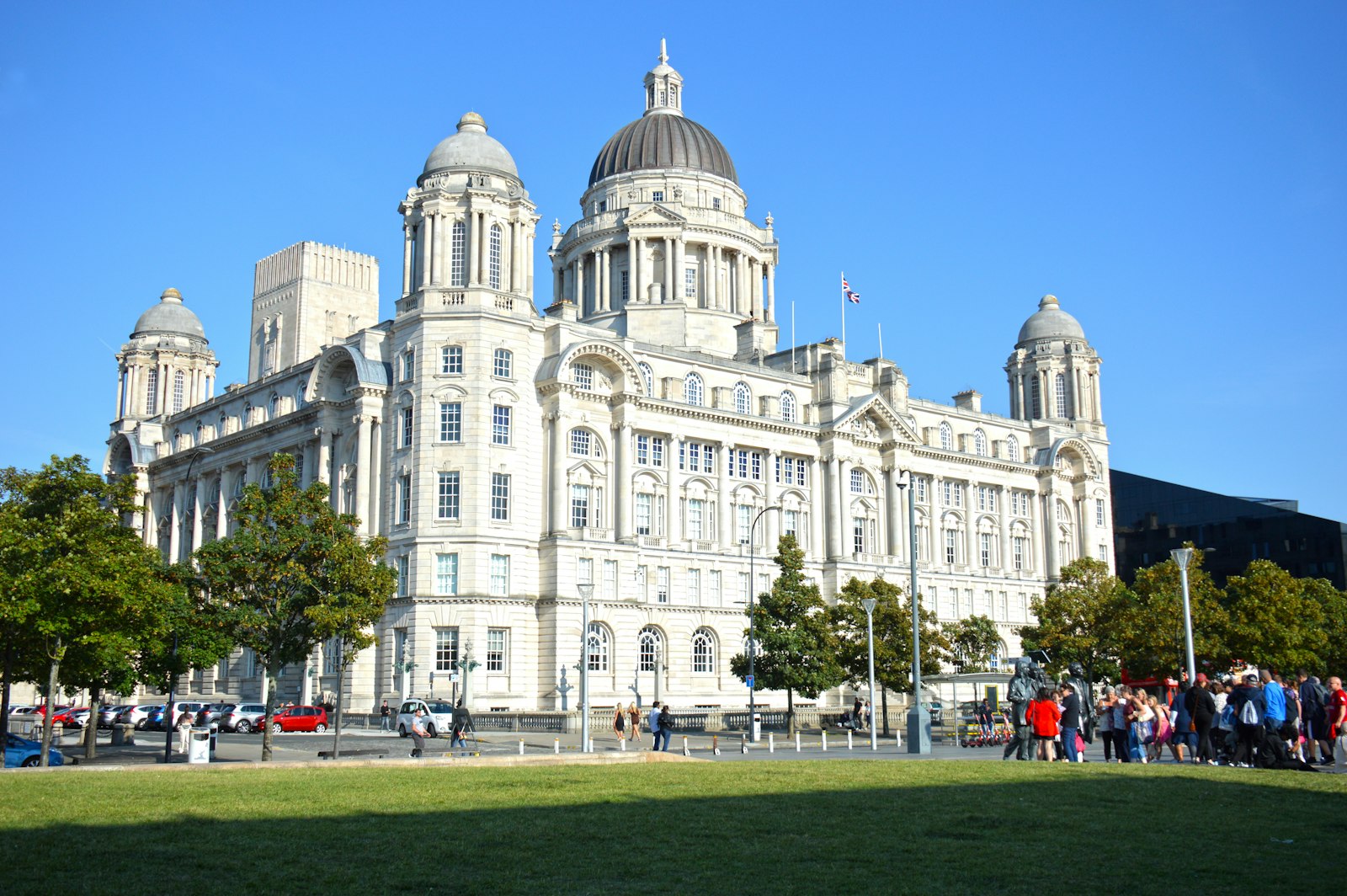 Photo of a large white building with a dome and many people walking around.