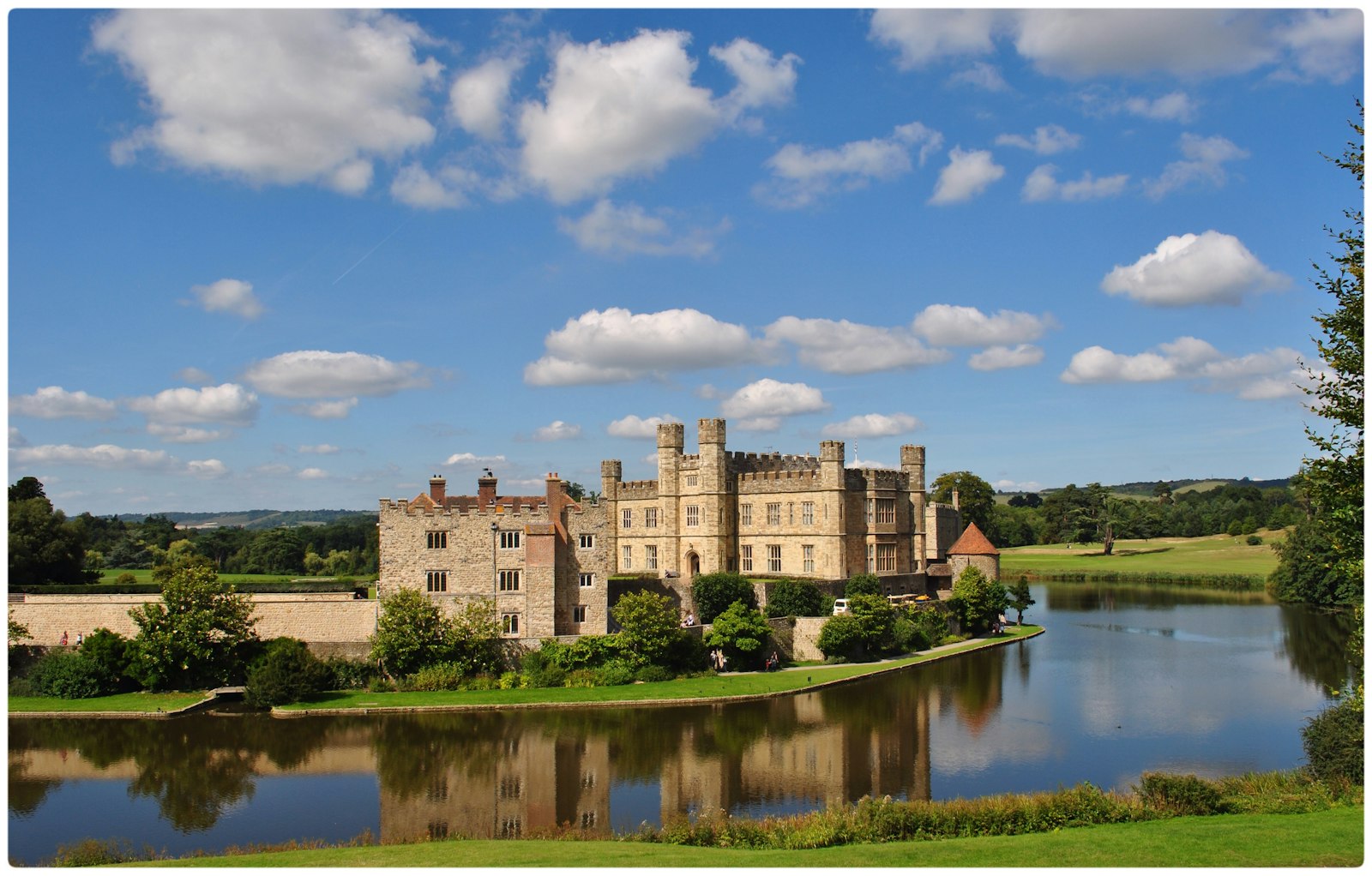 Photo of brown concrete castle with moat during daytime.