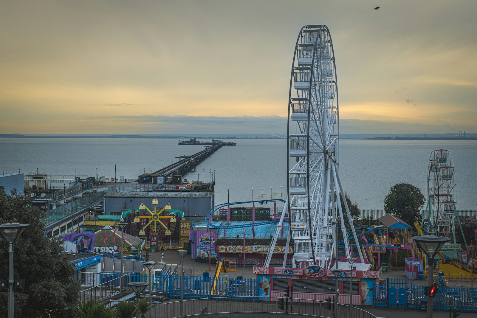 Photo of an amusement park with a ferris wheel in the foreground.
